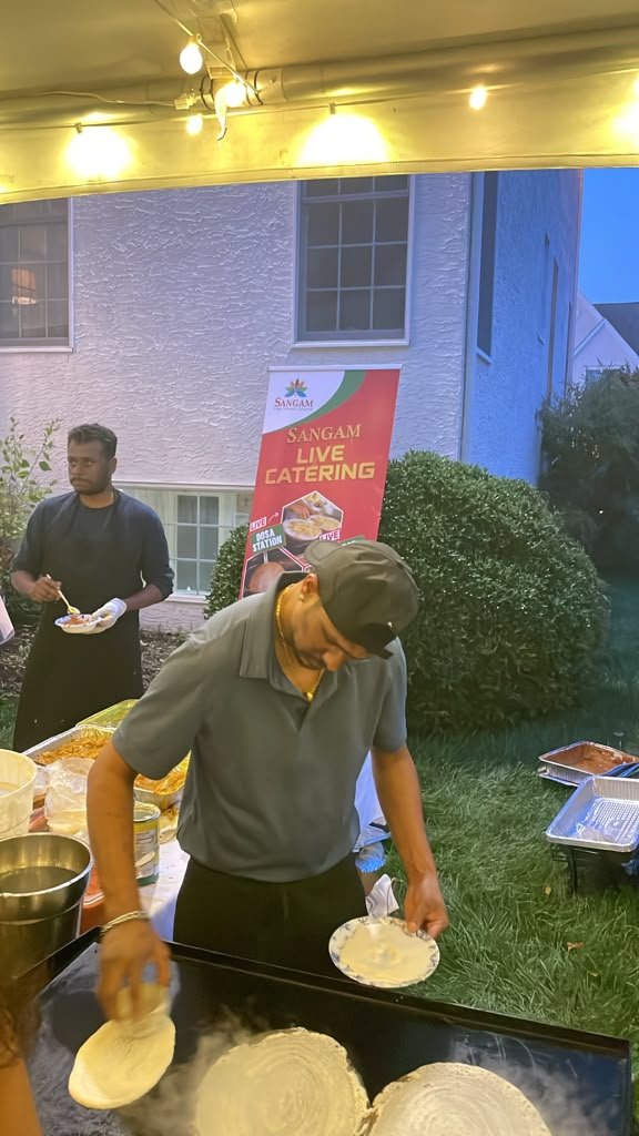 Sangam catering staff plating food at an event station